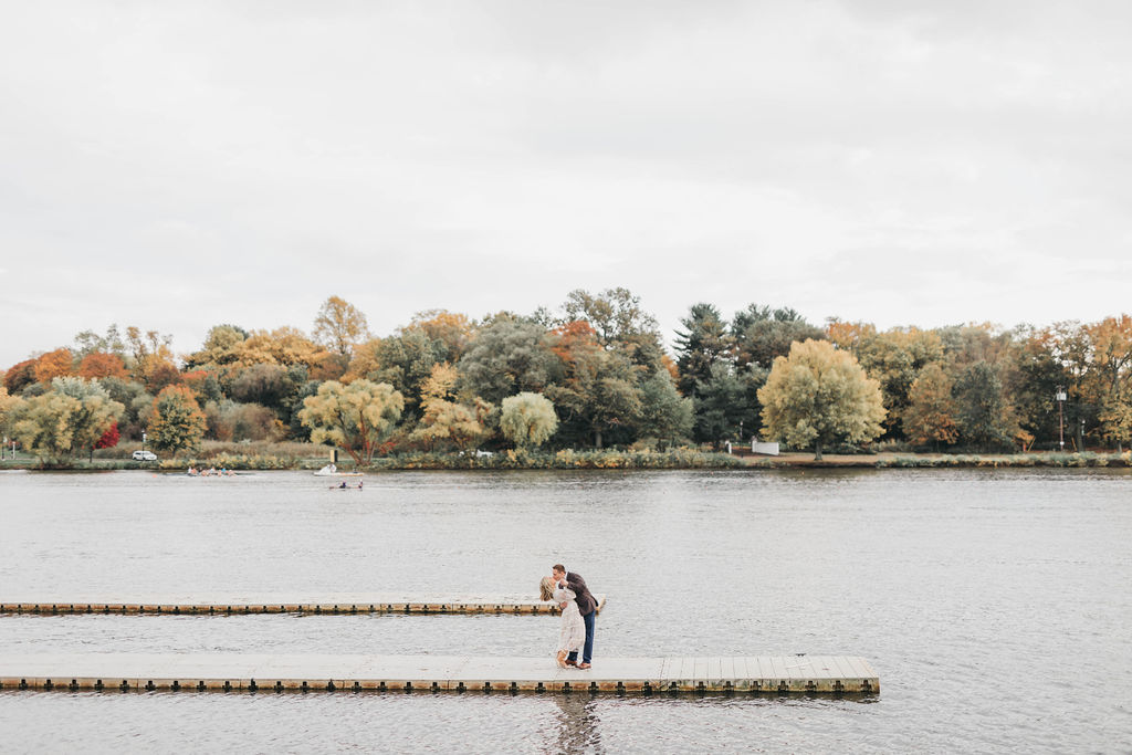 Couple posing on dock for fall engagement session photos in front of Cooper River in Collingswood NJ