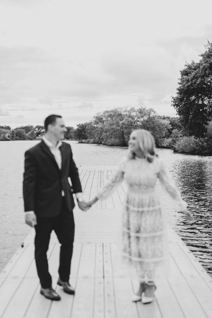 Black and white photo of couple posing on dock for fall engagement session photos in front of Cooper River in Collingswood NJ