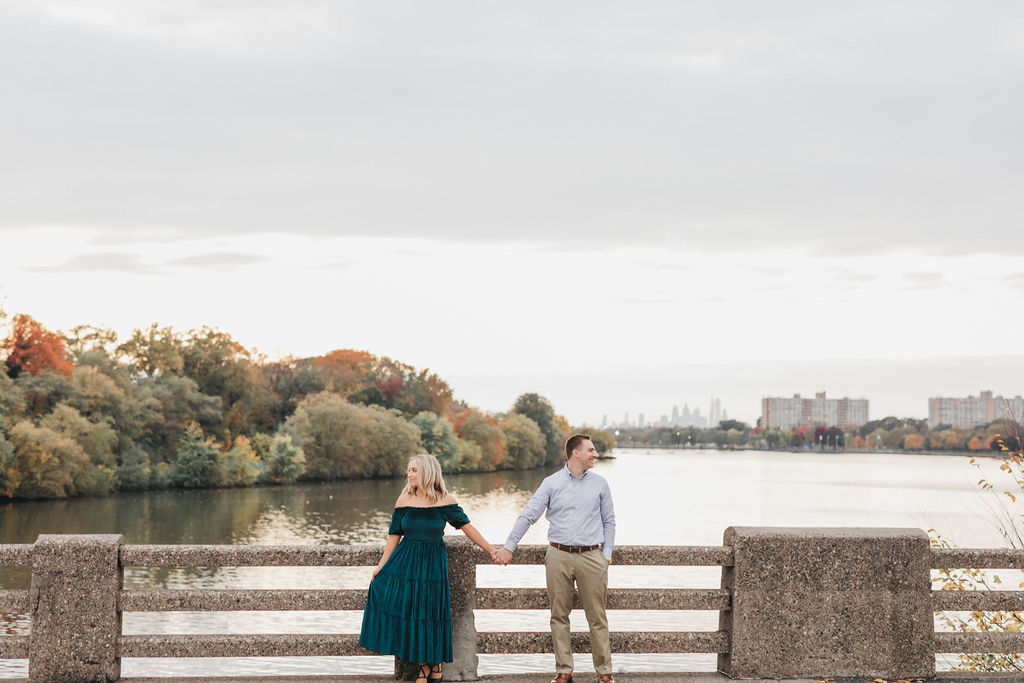 Couple posing for fall engagement session photos in front of Cooper River in Collingswood NJ