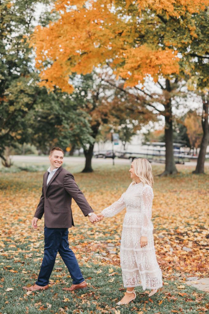 Couple holding hands in fall engagement session photo in Cooper River Park Collingswood NJ