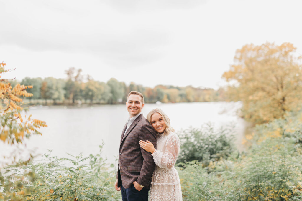 Couple posing for fall engagement session photos in front of Cooper River in Collingswood NJ
