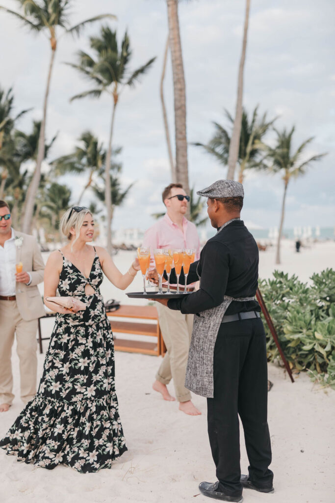 photo of a Hyatt Ziva staff member holding tray full of orange fruity  cocktails for wedding reception on the beach a destination wedding in the Dominican Republic