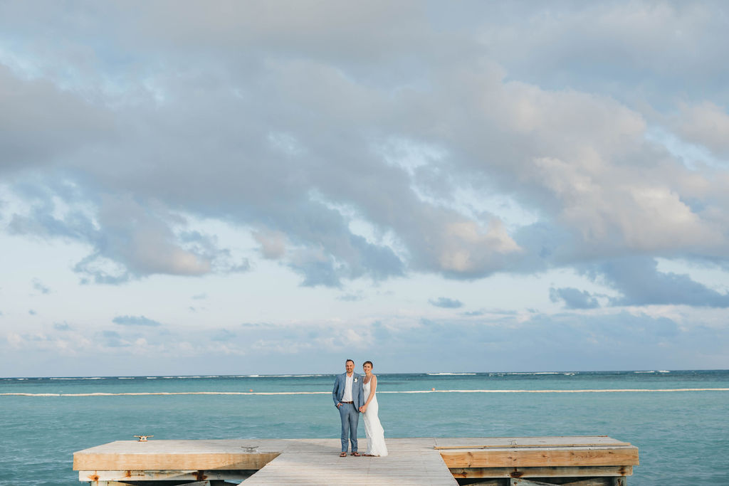 Bride and groom on the pier holding each other smiling at camera