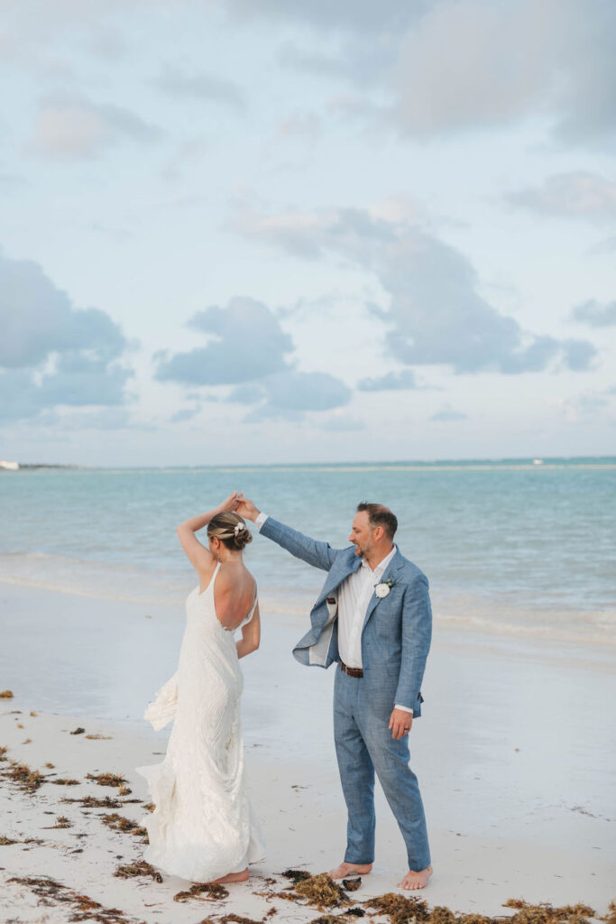 Groom spinning his bride on the edge of the clear turquoise water of the beach in Punta Cana Dominican Republic