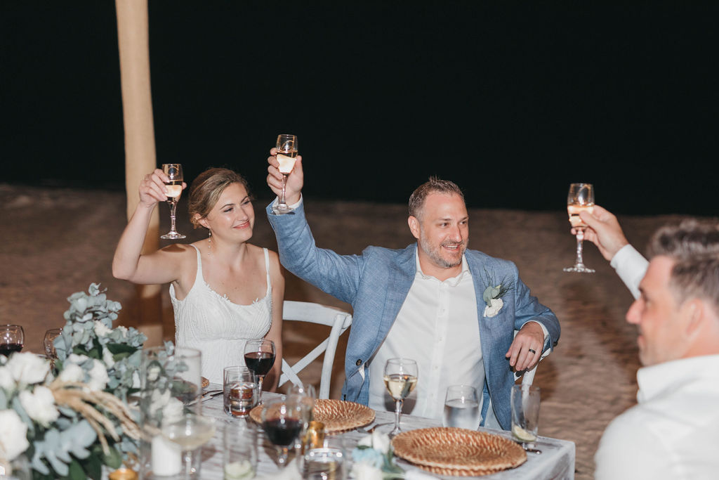 Photo of bride and groom holding glasses of champagne at reception during destination wedding in the Dominican Republic