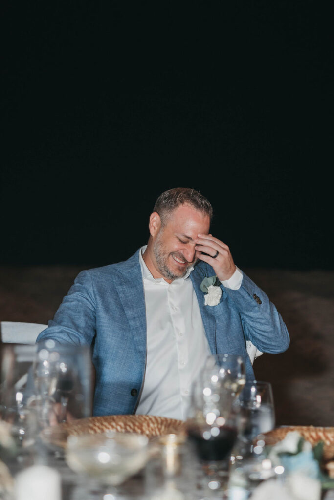 photo of groom laughing while sitting at reception during destination wedding in the Dominican Republic