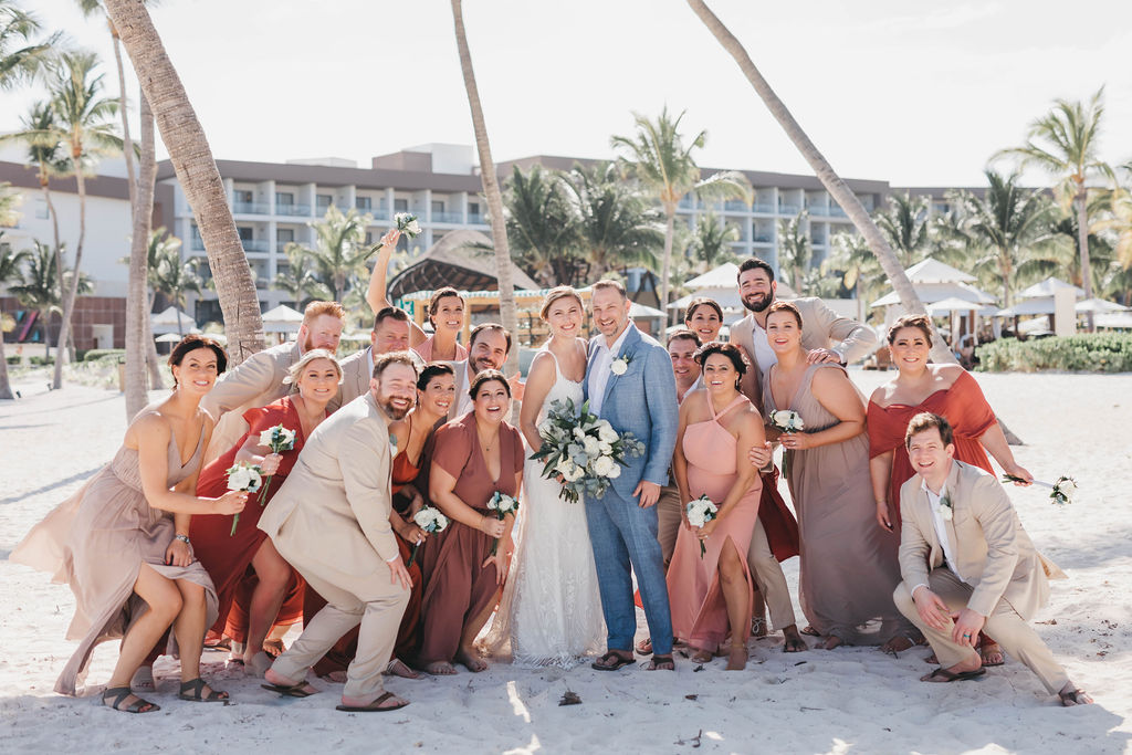 Large group of Bridesmaids and groomsmen pose with bride and groom on the beach
