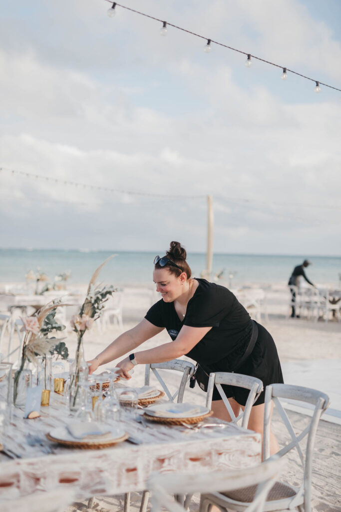 Woman setting table for beachside wedding reception
