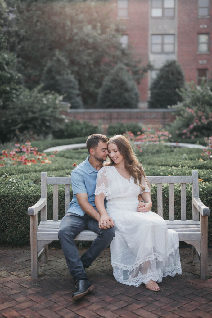 Couple sits on a wooden bench in front of manicured floral garden at F&M college in Lancaster PA