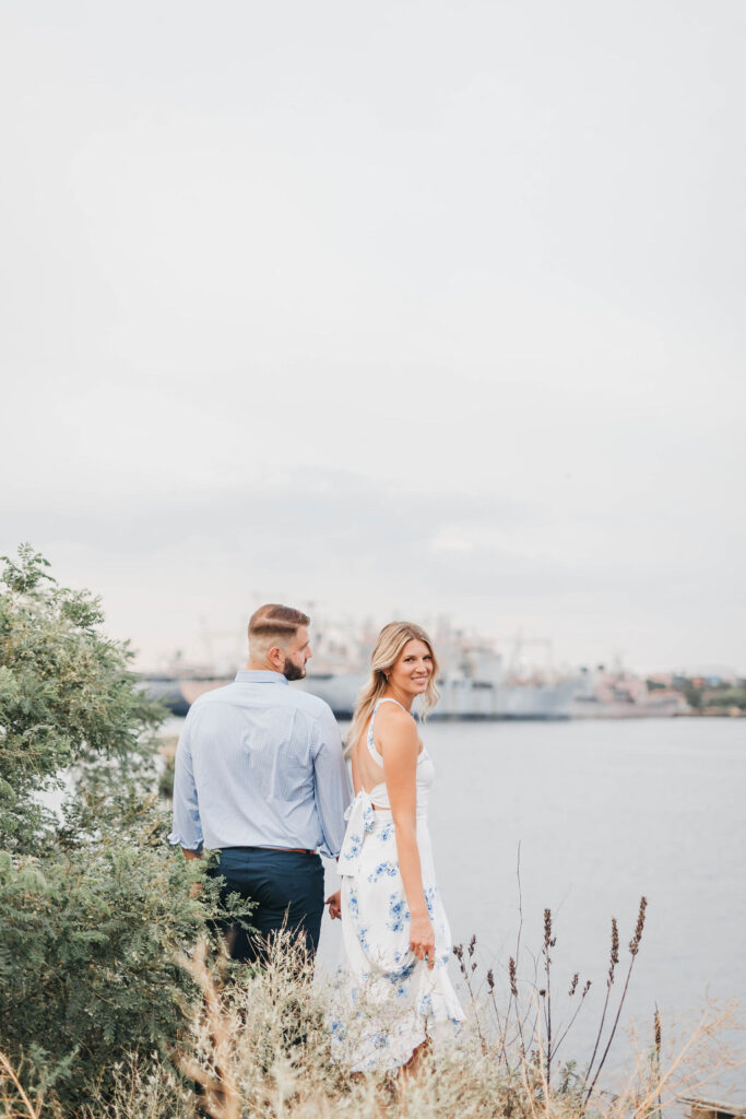 Couple stands facing the Philadelphia Naval Yard while holding hands