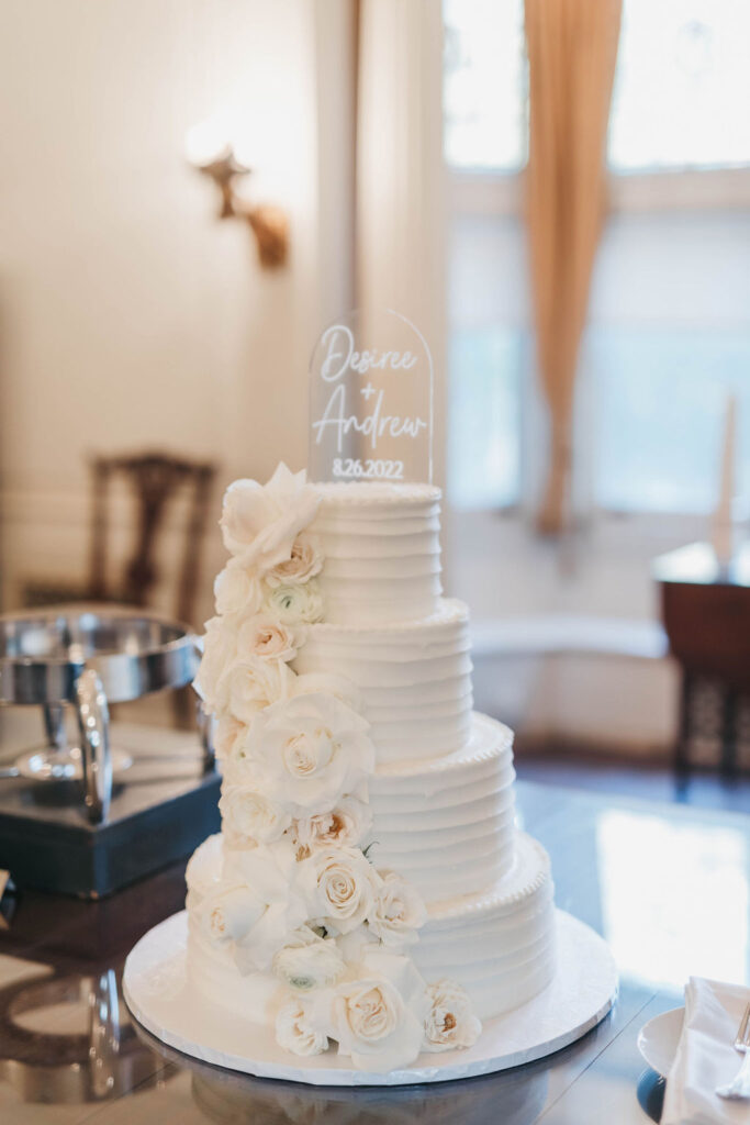 4 tier white iced wedding cake with white florals cascading down the left side