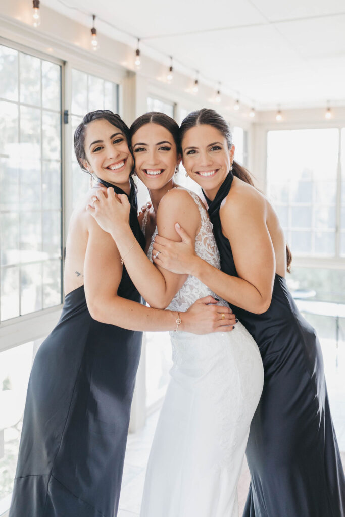 A bride wearing white in between two bridesmaids wearing black halter style dresses | Lauren E. Bliss Photography Luxury PA Wedding Photographer
