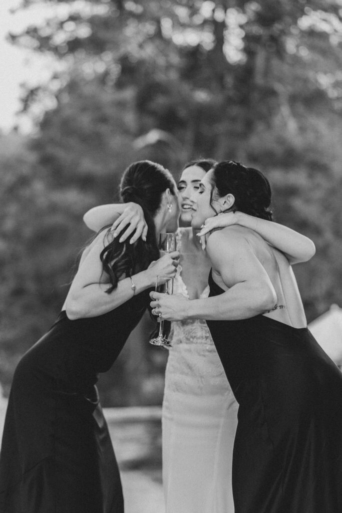 Black and white photo of bride hugging her two bridesmaids | Lauren E. Bliss Photography Luxury PA Wedding Photographer