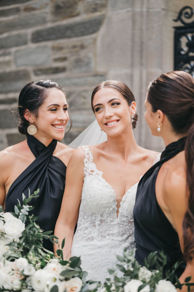 Two matrons of honor look on as the bride smiles
