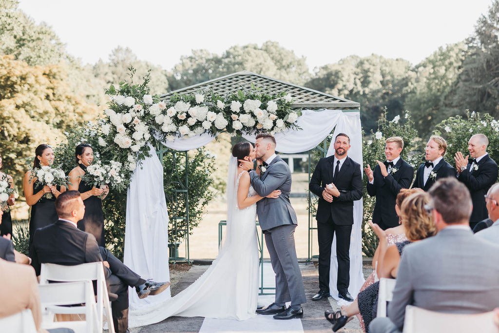 Bride and groom kissing under floral gazebo in the North Garden at Greystone Hall venue in West Chester PA | Lauren E. Bliss Photography