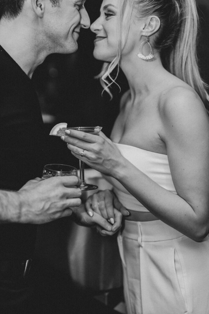 Black and white photo of bride and groom holding cocktail glasses