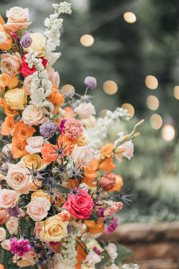 Colorful pink orange and yellow floral arch | Colorful wedding photography by Lauren E. Bliss Photography