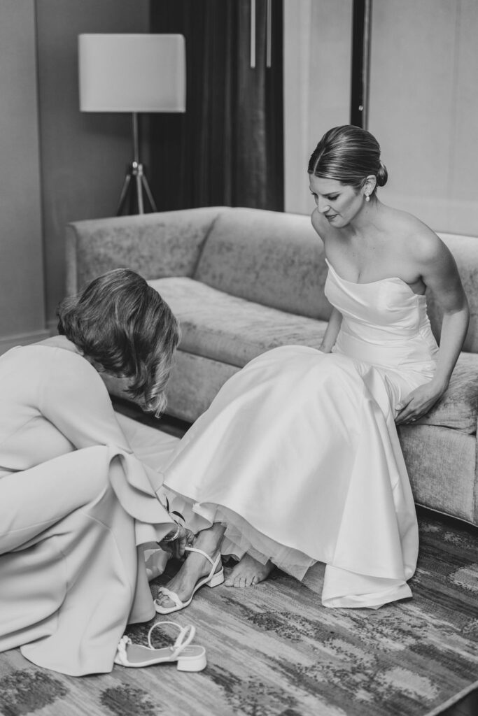 Mother of the bride helps her daughter put on her wedding shoes