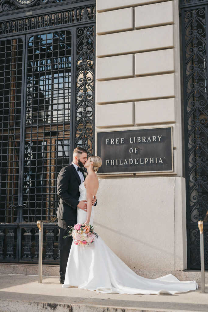 Bride and groom kiss on the steps of the Free Library of Philadelphia