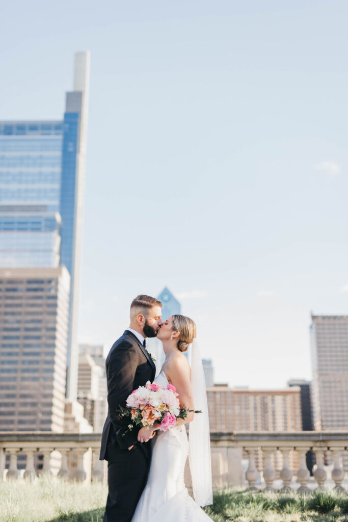 Bride and groom kiss during golden hour on the Free Library of Philadelphia rooftop
