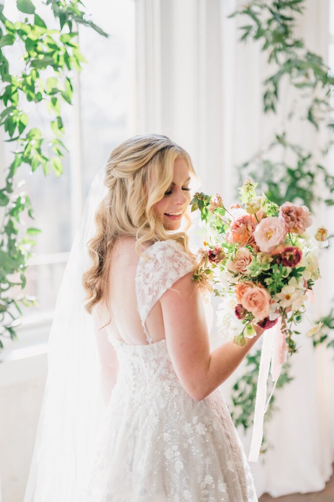 Bride looks down and smiles while holding a hand tied wedding bouquet of fall colors