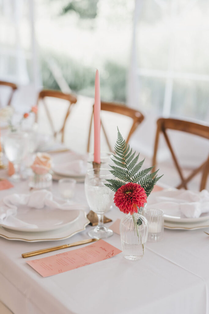 Banquet style wedding tablescapes decorated with a peach and pink color palette, gold flatware, and white linens