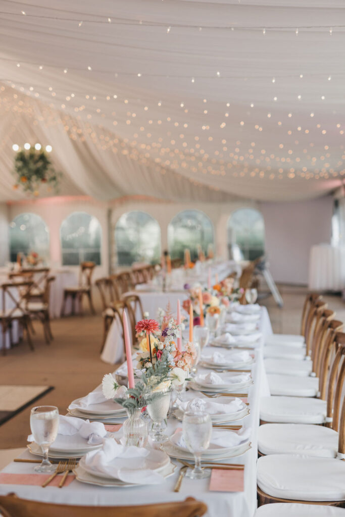 Banquet style wedding tablescapes decorated with a peach and pink color palette, gold flatware, and white linens