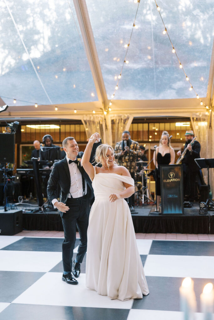 Bride and groom dance together on black and white checkered dance floor under a clear tent at Winterthur Museum and Gardens