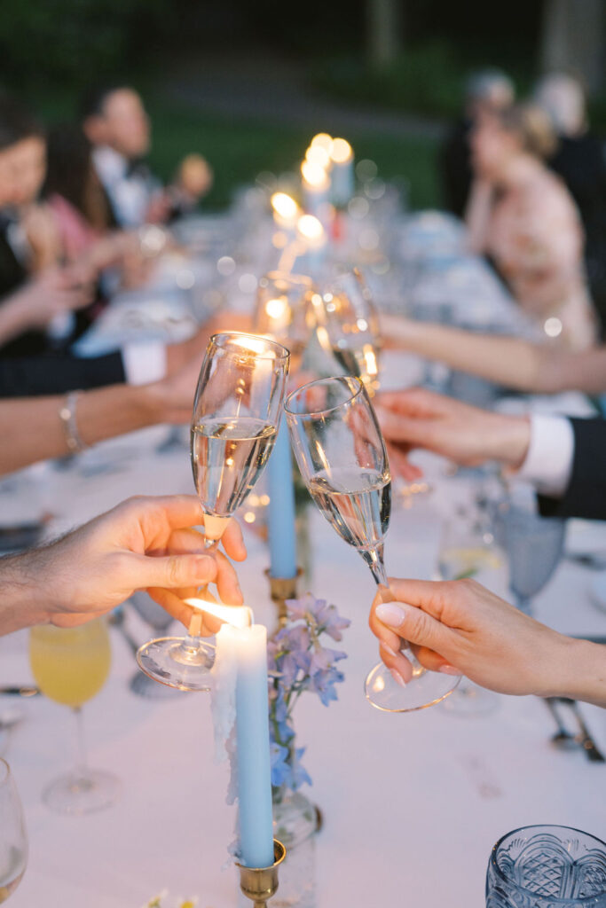 Close up of champagne flutes clinking over a long wedding banquet table at Winterthur Museum and Gardens