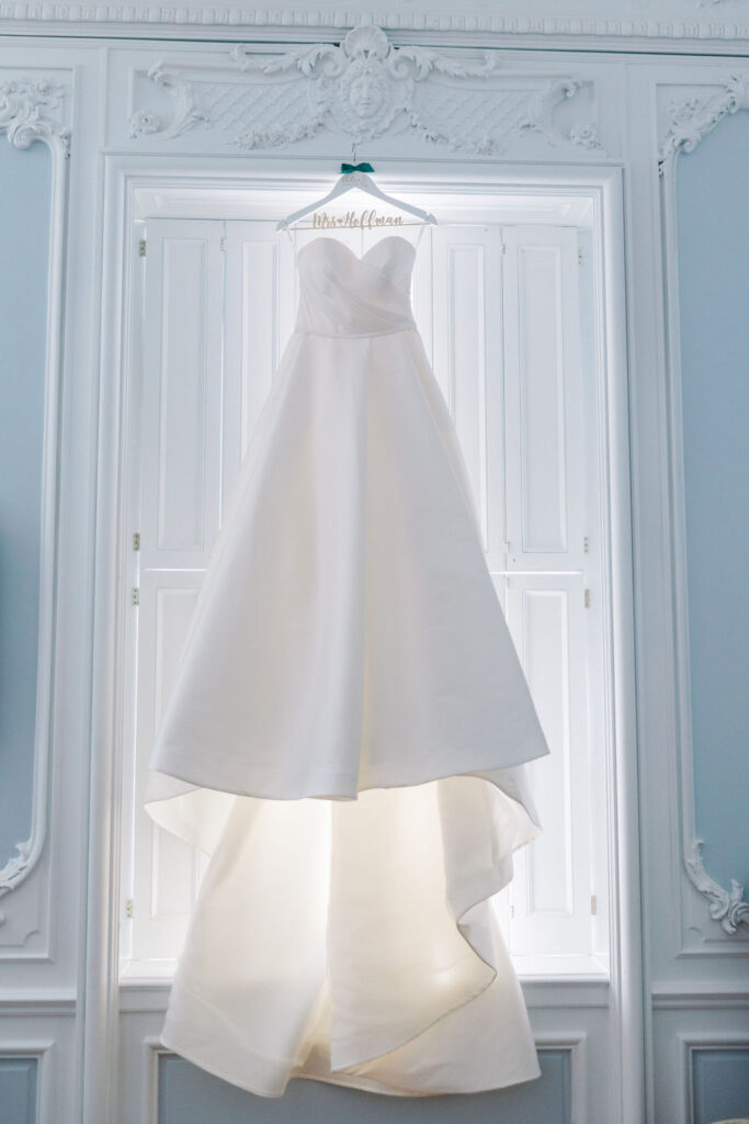 Bridal ballgown hangs in front of window | Lauren Bliss Photography at Elkins Estate in Philadelphia