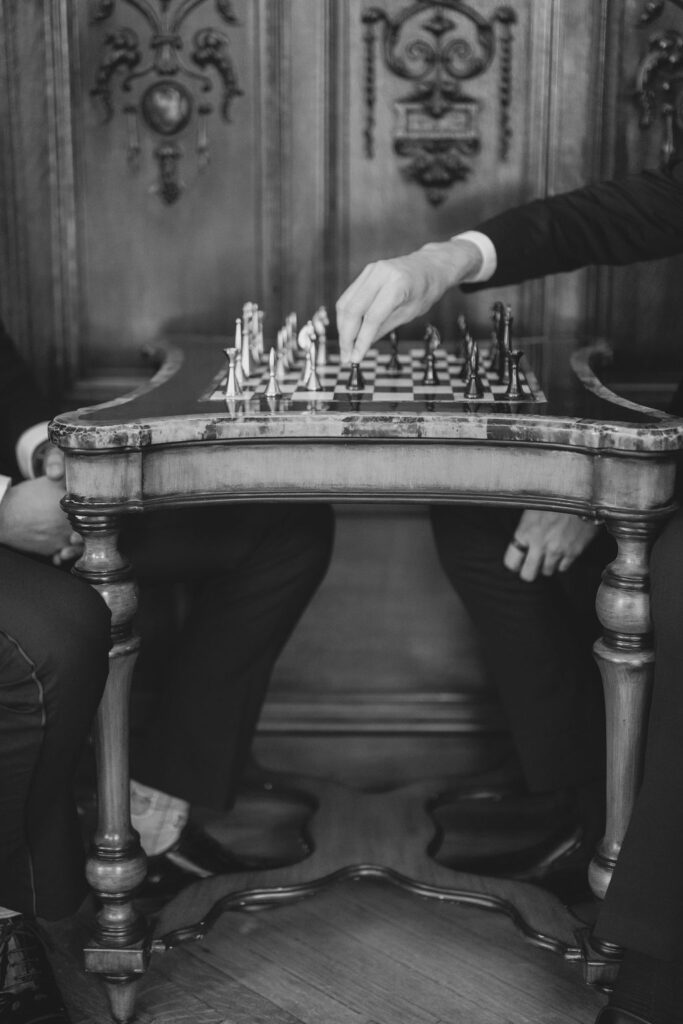 Two groomsmen play chess | Lauren Bliss Photography at Elkins Estate in Philadelphia