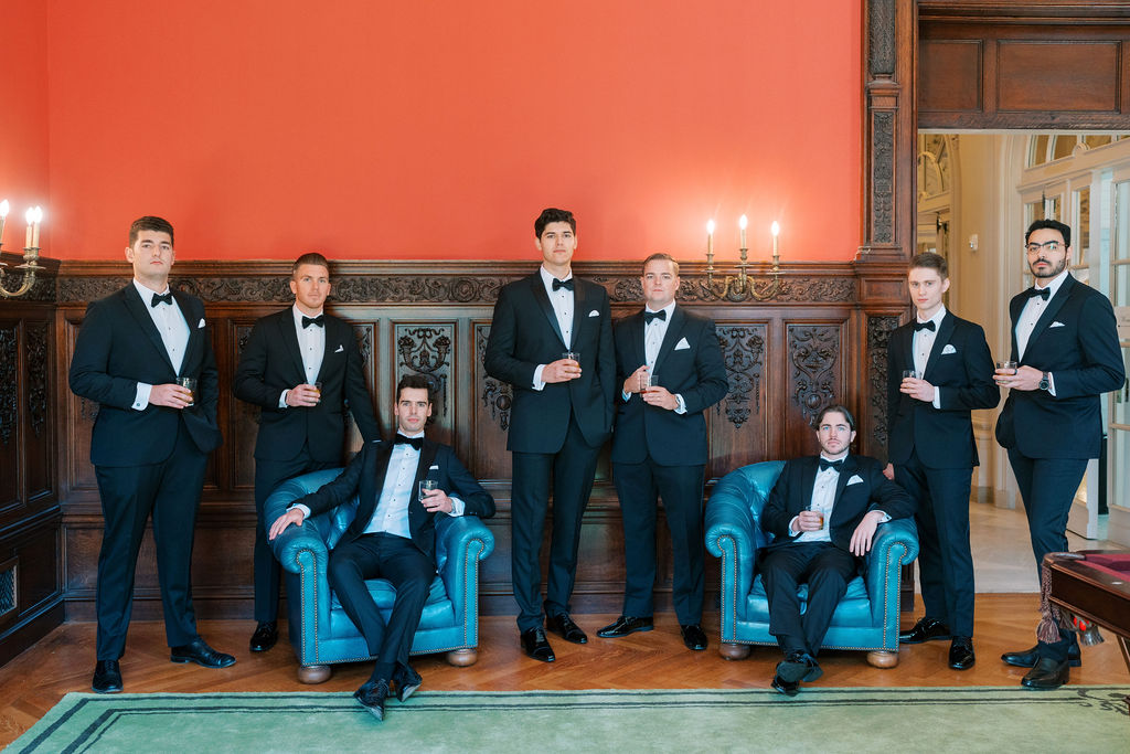 Eight groomsmen stand and sit together to pose for a photo | Lauren Bliss Photography at Elkins Estate in Philadelphia