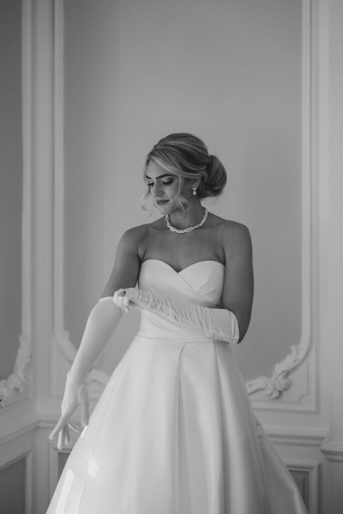 Bride puts on an elbow length glove | Lauren Bliss Photography at Elkins Estate in Philadelphia