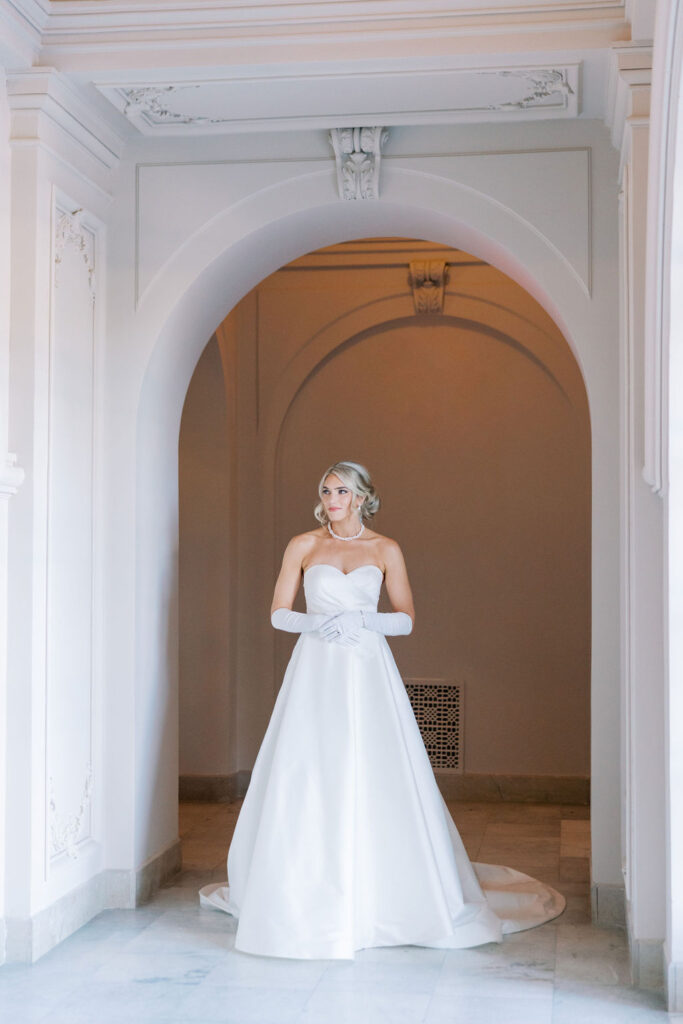 Bride stands in an archway at the end of an ornate hallway | Lauren Bliss Photography at Elkins Estate in Philadelphia