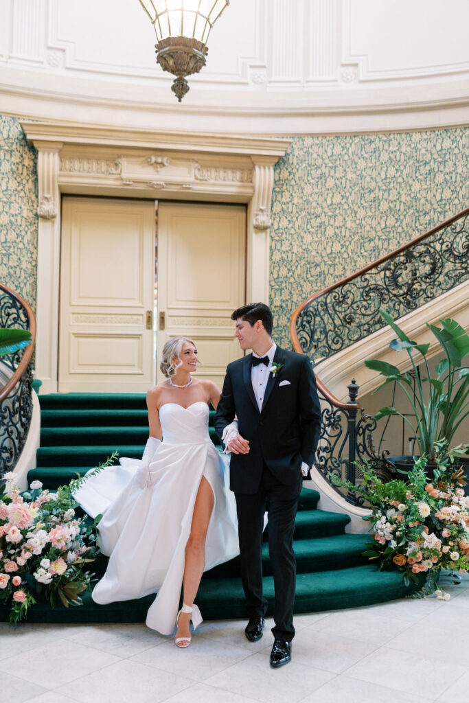 Bride and groom descend emerald green carpeted staircase | Lauren Bliss Photography at Elkins Estate in Philadelphia