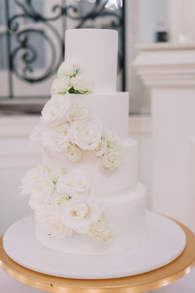 Four tiered white wedding cake decorated with white roses | Wedding Photography by Lauren Bliss at the Cescaphe Ballroom Philadelphia