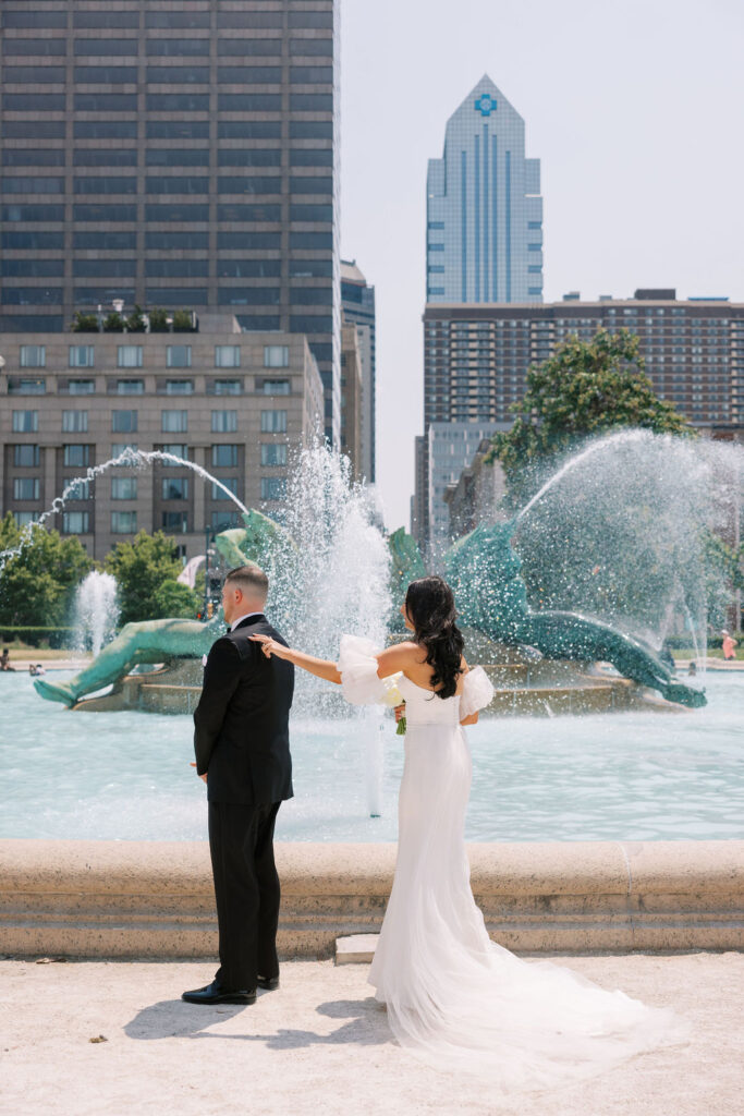 Bride taps on grooms shoulder during first look photos at Swann Memorial fountain | Wedding Photography by Lauren Bliss at the Cescaphe Ballroom Philadelphia