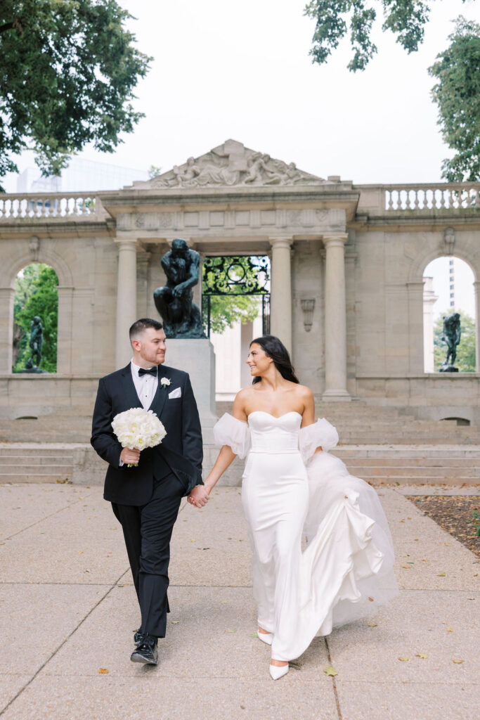 Bride and groom walk in front of Auguste Rodin’s Bronze statue of The Thinker | Wedding Photography by Lauren Bliss at the Cescaphe Ballroom Philadelphia