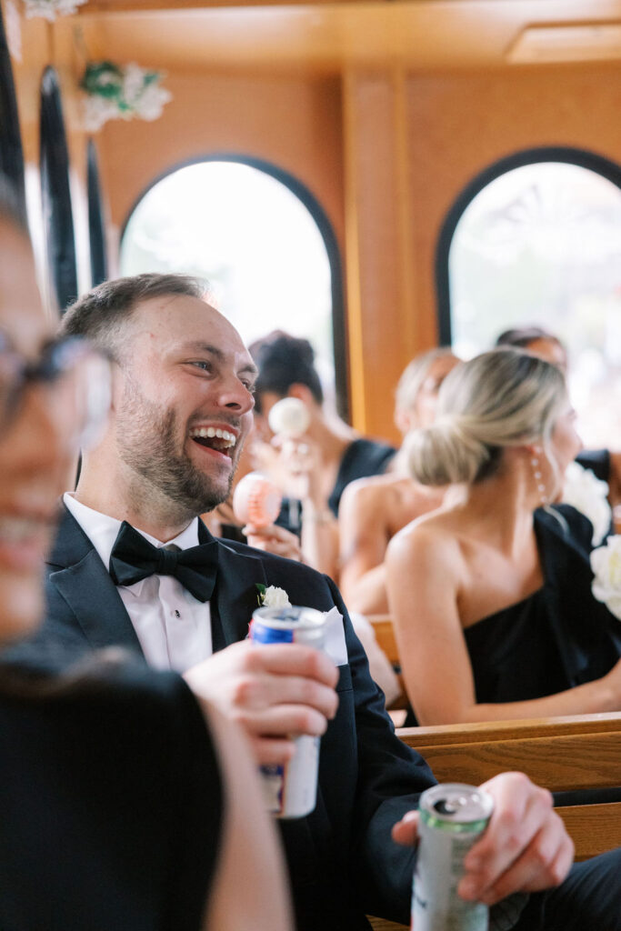 Man laughs while double fisting drinks inside wedding shuttle | Wedding Photography by Lauren Bliss at the Cescaphe Ballroom Philadelphia