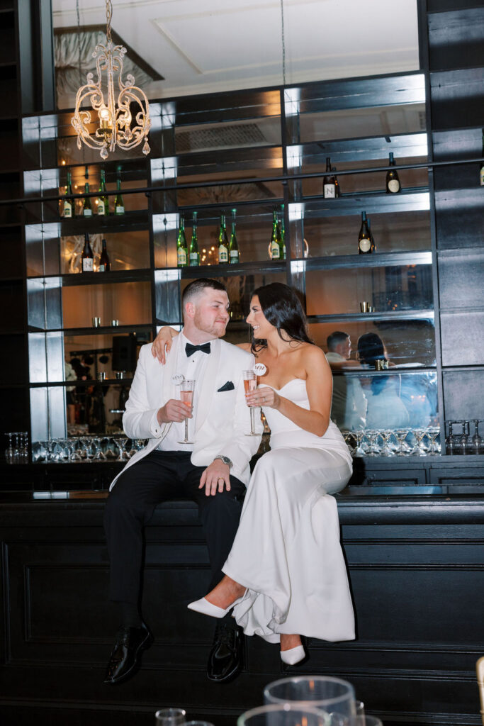 Bride and groom sits on bar top | Wedding Photography by Lauren Bliss at the Cescaphe Ballroom Philadelphia