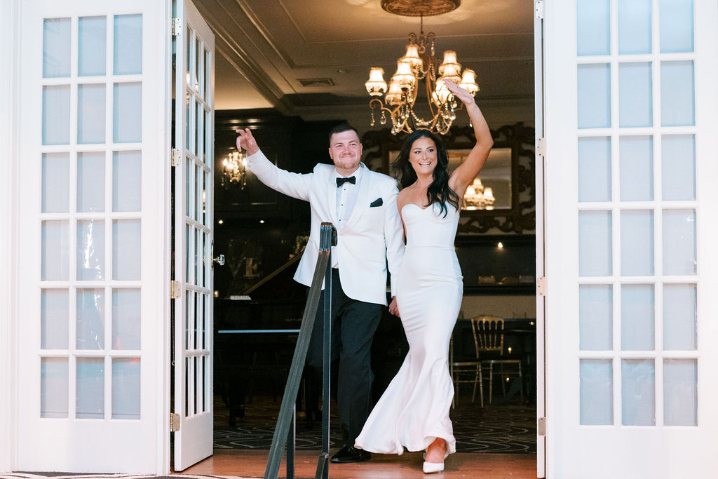 Bride and groom walk out of venue with their hands raised | Wedding Photography by Lauren Bliss at the Cescaphe Ballroom Philadelphia