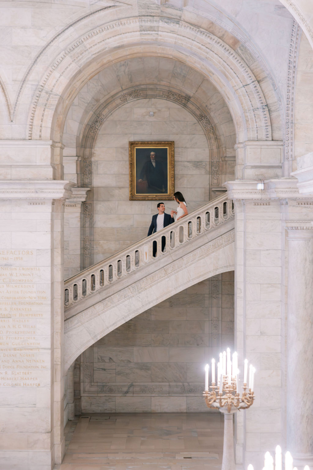 Couple stands on stone staircase and kisses inside the New York Public Library | Lauren Bliss Photography