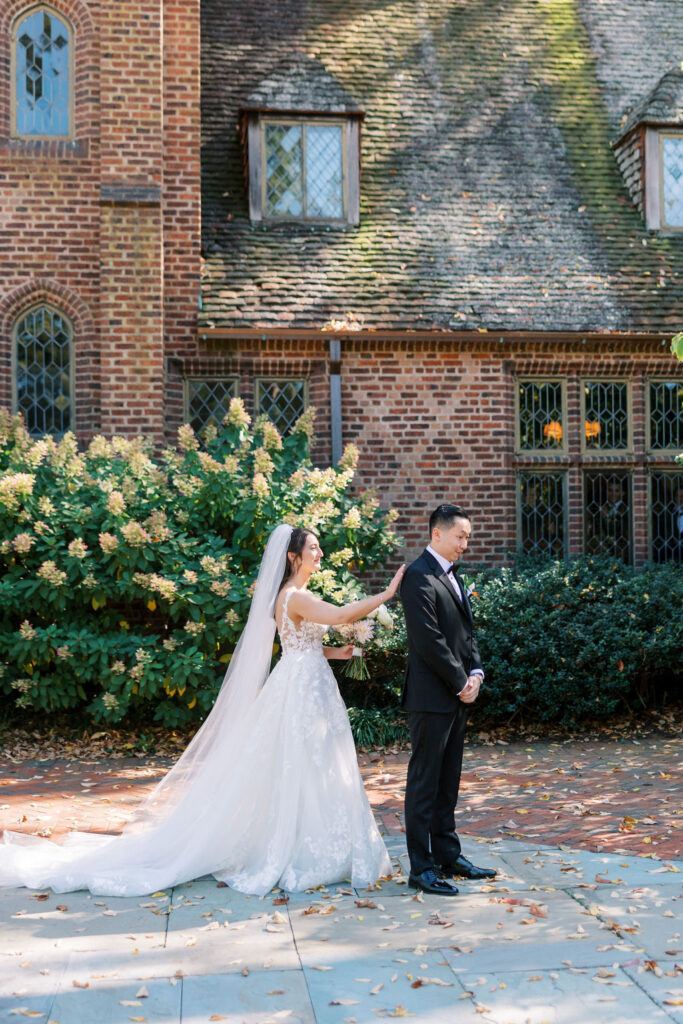 Bride taps grooms shoulder in front of white hydrangea bush at Aldie Mansion on their wedding day | Lauren Bliss Photography