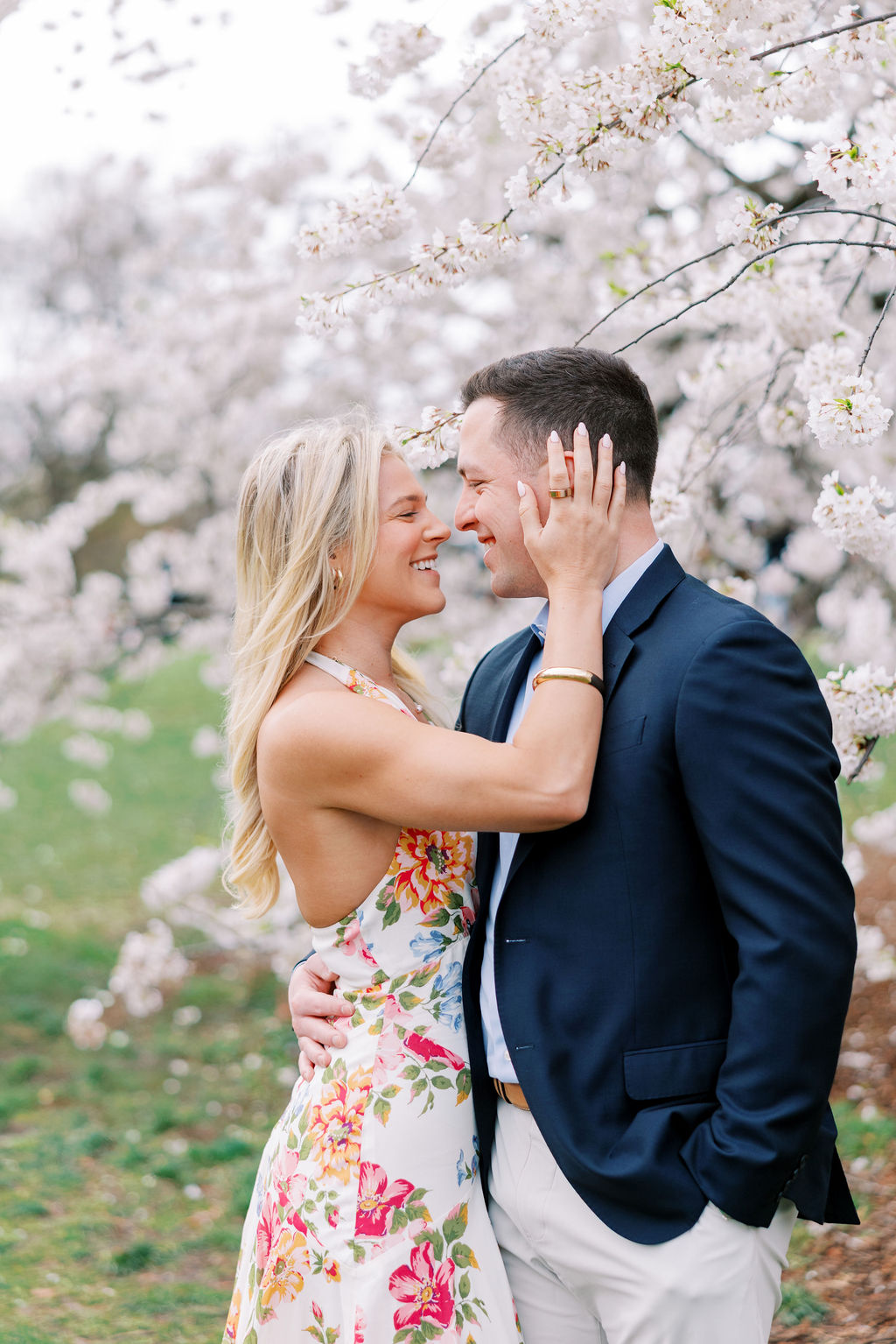 Engaged couple stands in front of cherry blossom tree in Central Park NYC during engagement photo session | Lauren Bliss Photography