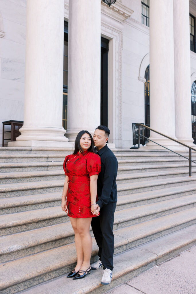 Woman in red mini dress with puff sleeves leans back against man wearing all black outfit for engagement photos in Philadelphia | Lauren Bliss Photography
