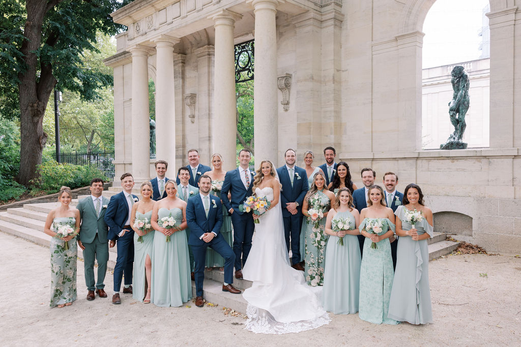 Bride and groom surrounded by 21 person wedding party wearing sage green and navy | Philadelphia Wedding at Waterworks Cescaphe by Lauren Bliss Photography