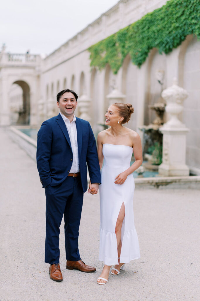 Elegant Longwood Gardens engagement session image of couple posing in front of a marble fountain by Lauren Bliss Photography, ideal for showcasing on your wedding website