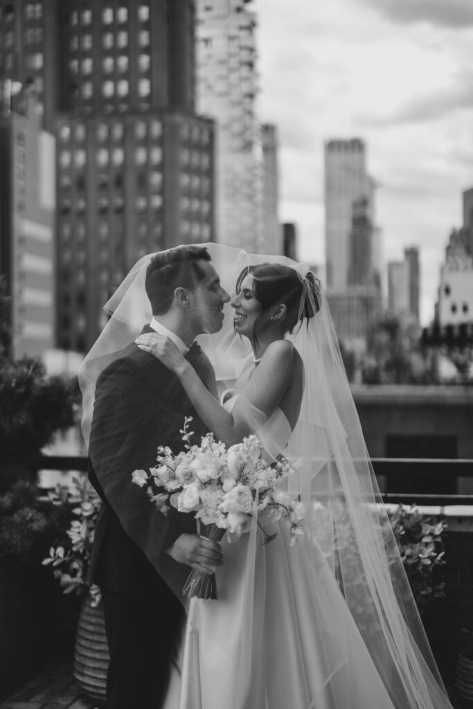 Romantic black and white wedding portrait of bride and groom under a veil with Manhattan skyscrapers in the background at Tribeca 360 rooftop in NYC.