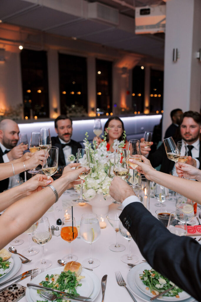 Guests raising champagne glasses for a wedding toast at Tribeca Rooftop reception in New York City.