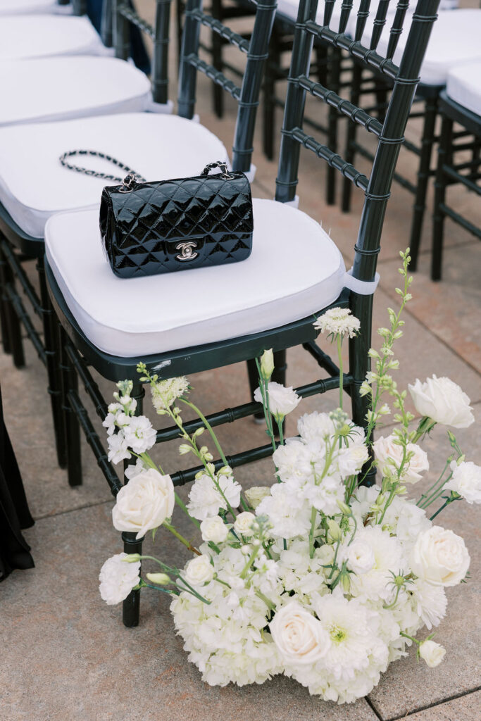 Chic black Chanel handbag on a ceremony chair with white floral aisle décor at Sam and Andrew’s Tribeca 360 rooftop wedding in New York City.